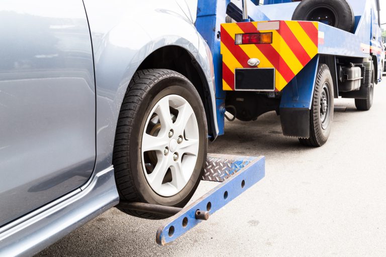 Tow truck towing a broken down car on the street